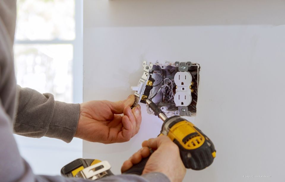 Person mit gelben Handschuhen installiert ein weißes Fenster mit Glasscheiben.