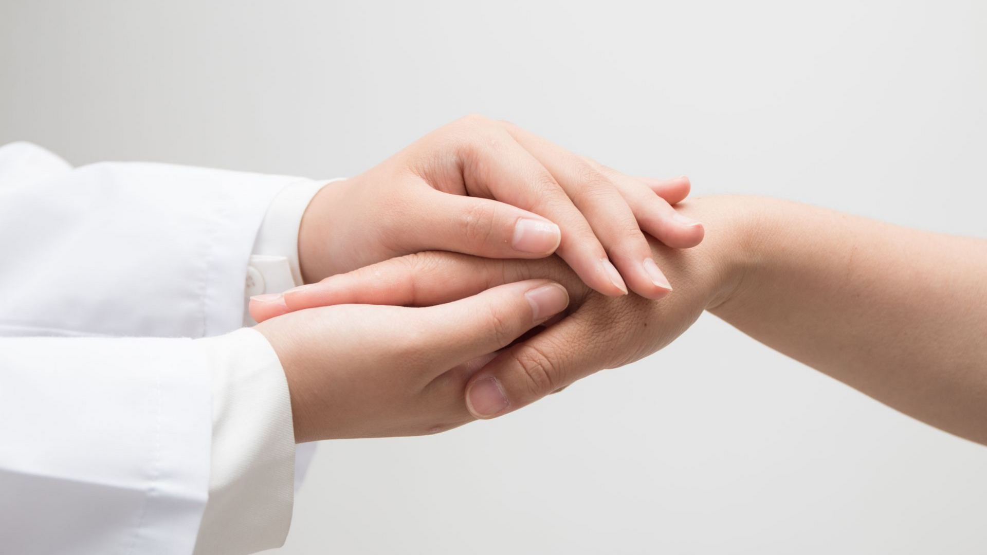 Les mains d'un médecin tiennent la main d'une patiente.
