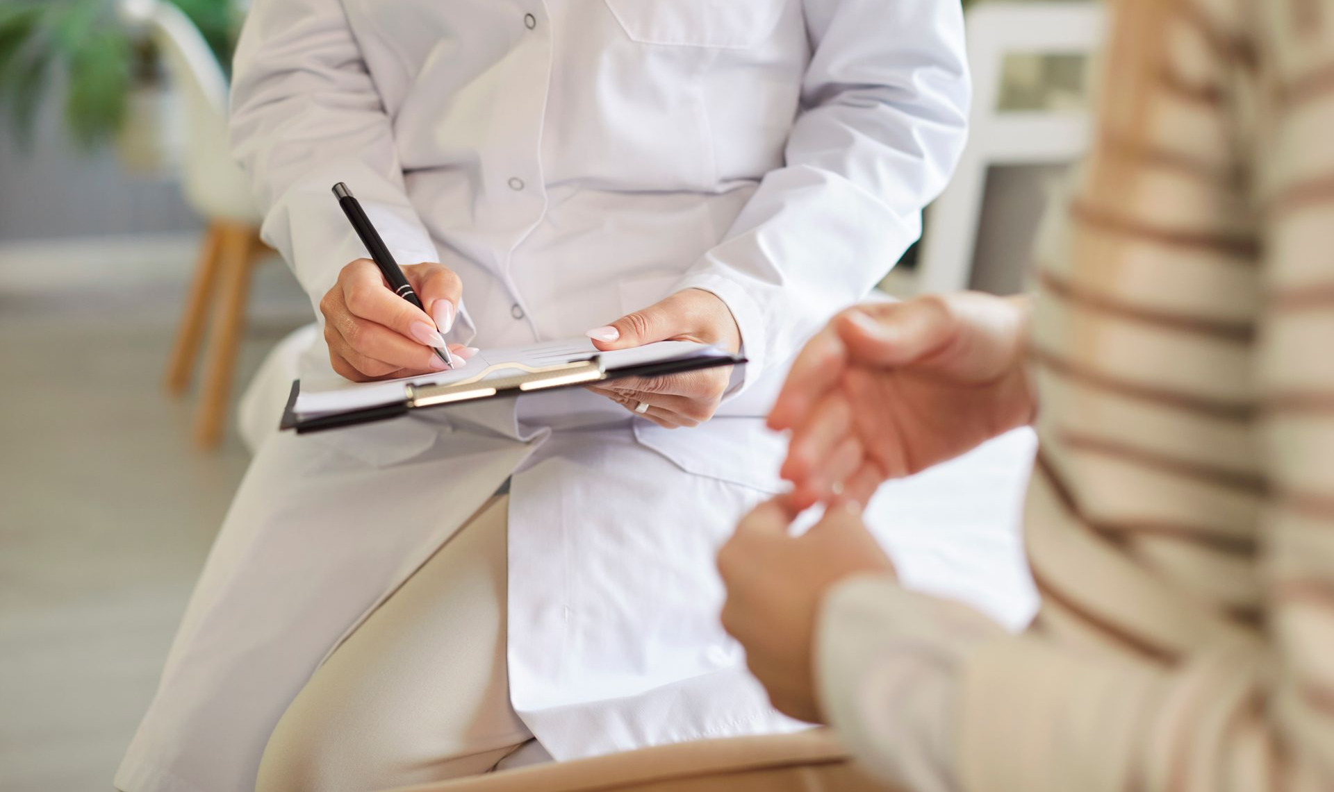 La main d'un médecin posée sur le dos d'un patient. Le médecin porte une blouse blanche. La scène semble se dérouler dans un cabinet médical.