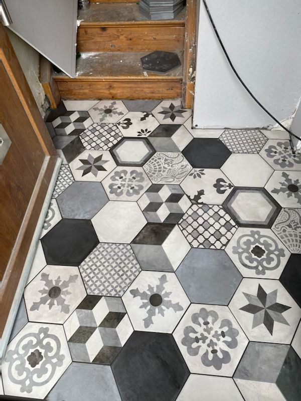 Carrelage hexagonal à motifs dans les tons de gris, de noir et de blanc au sol.