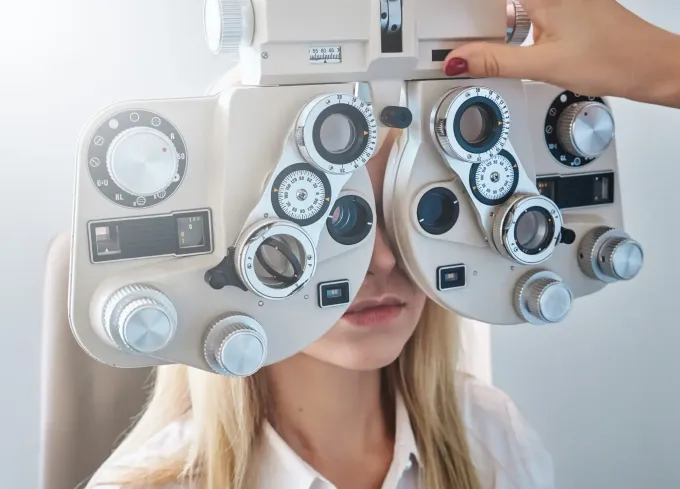 Una mujer se hace examinar los ojos con un foróptero en una oficina.