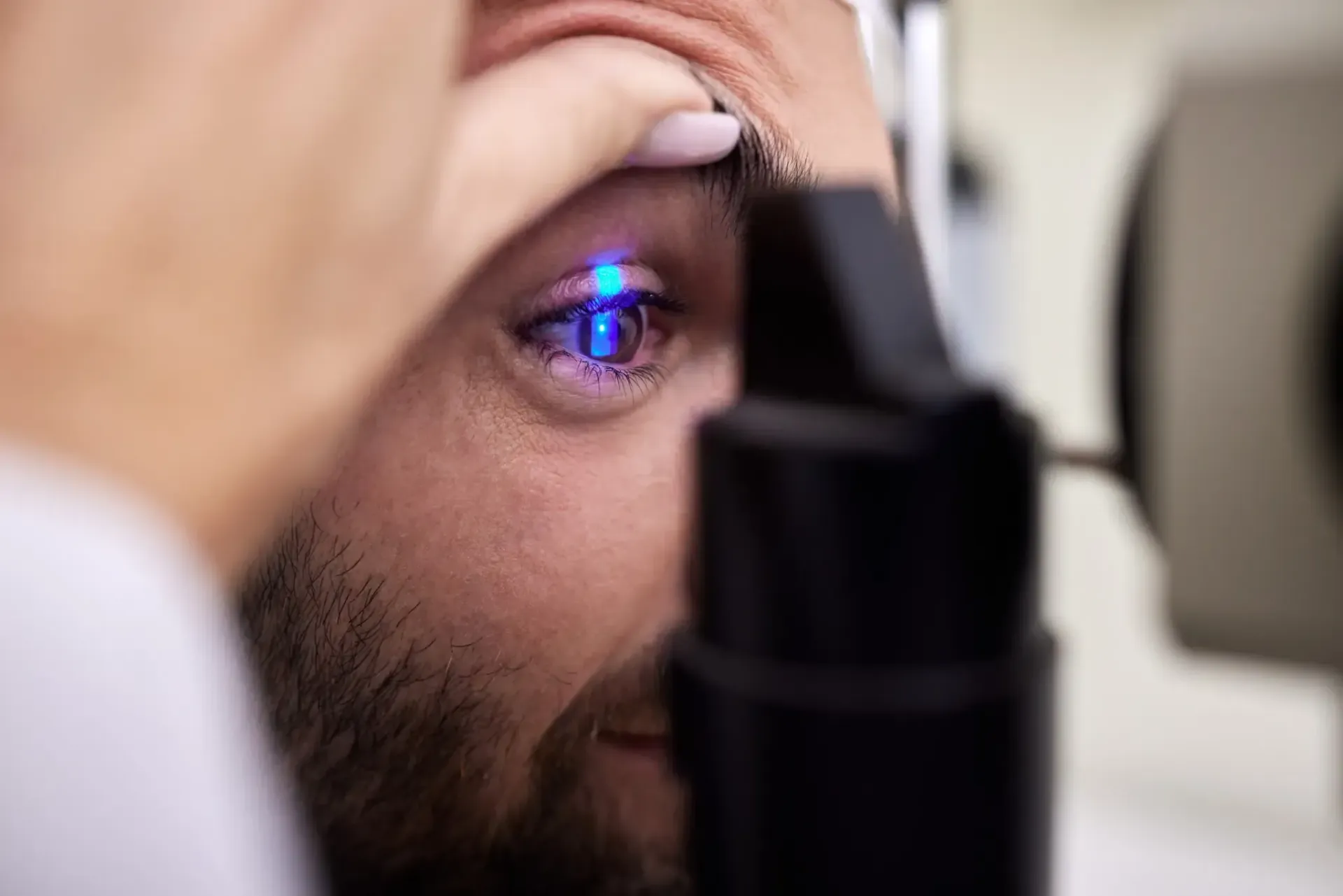 Un médico le examina el ojo a un hombre con luz azul.