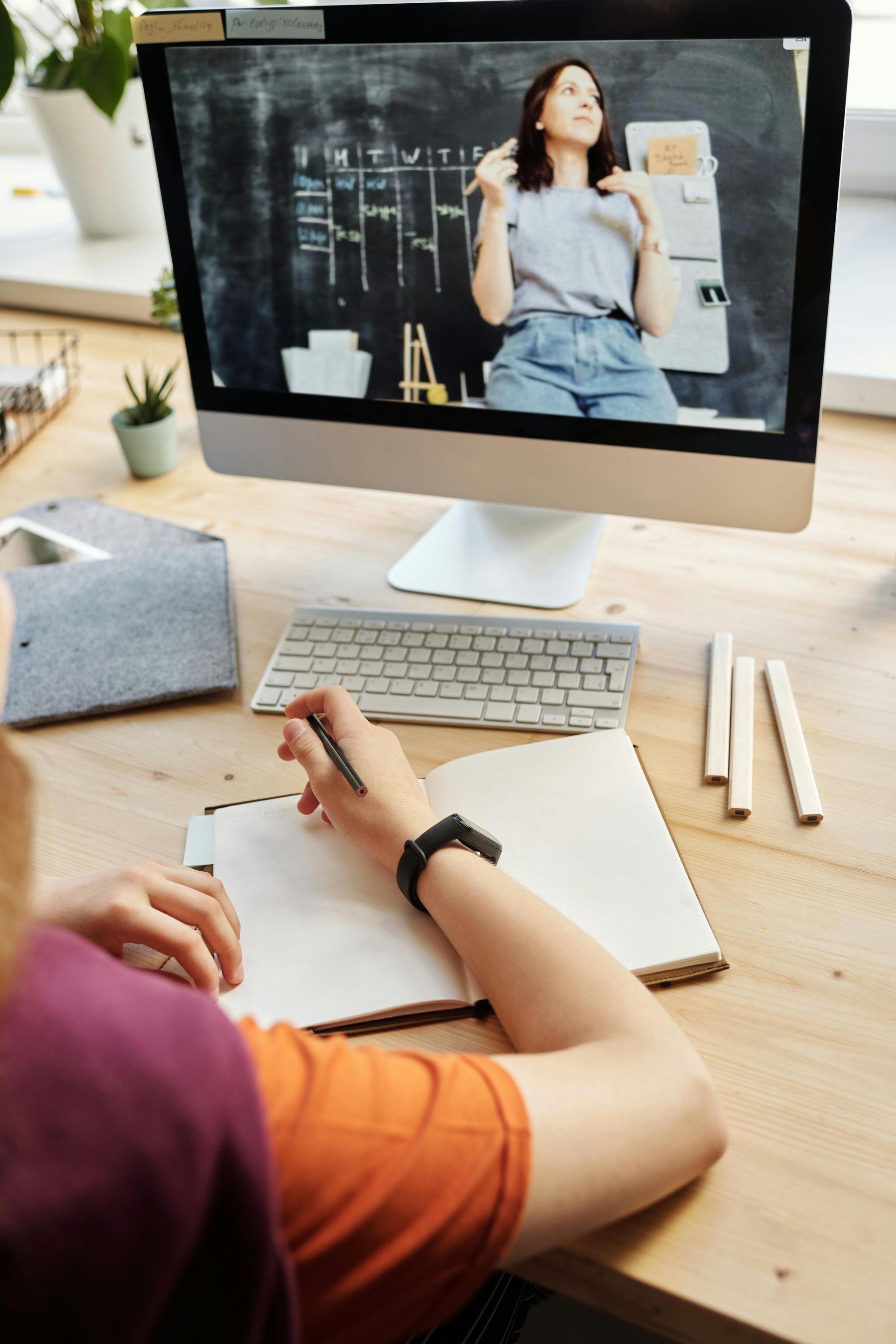 Una mujer está sentada en un escritorio mirando una pantalla de computadora.
