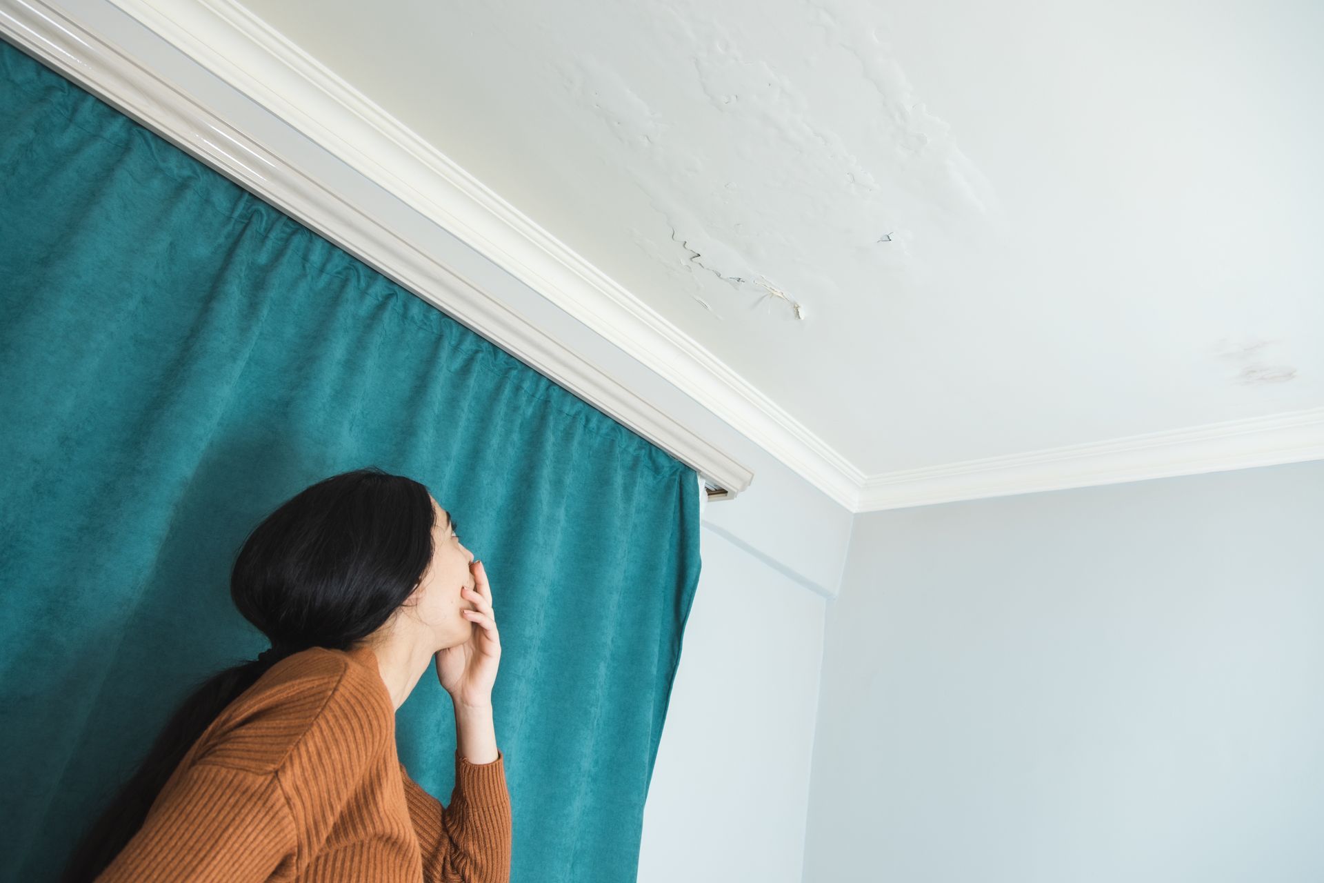 Un plafond avec de l'humidité et un rideau bleu