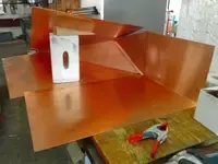 Dachdecker arbeitet auf dem Dach eines Gebäudes mit rosa Isolierung und Schindelbündeln.