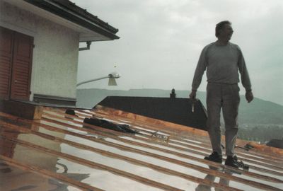 Weiße Garage mit schwarzem Dach und zwei passenden Lichtern auf beiden Seiten der geschlossenen Tür, auf einer Betonauffahrt.