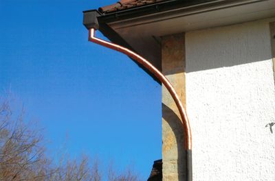 Braunes Dachrinnensystem an einem Gebäude, das Wasser sammelt.