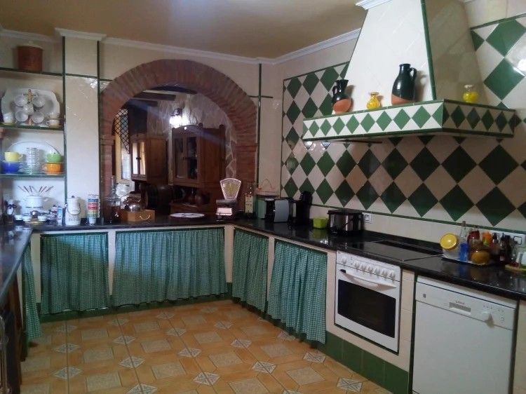 Cocina con azulejos de diamantes verdes y blancos, arco y gabinetes de madera.