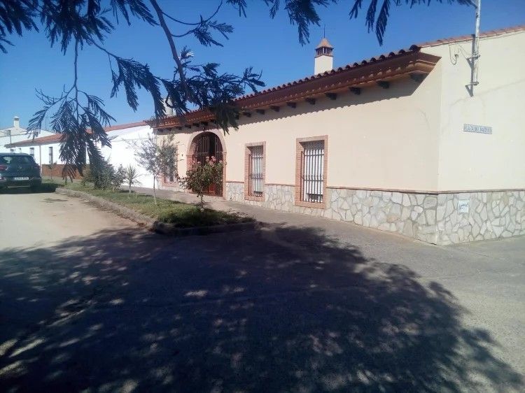 Edificio de color canela con base de piedra y techo de tejas en una calle