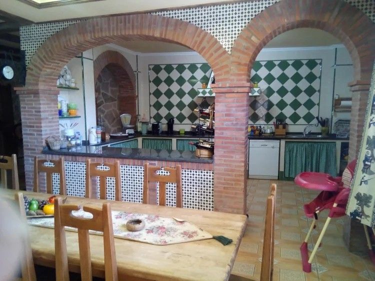 Cocina con arcos de ladrillo, salpicadero de azulejos de diamante, gabinetes de madera y juego de mesa de comedor.