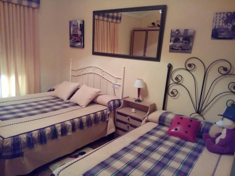 Piscina de agua azul frente a una casa estilo español con arcos, plantas y patio.