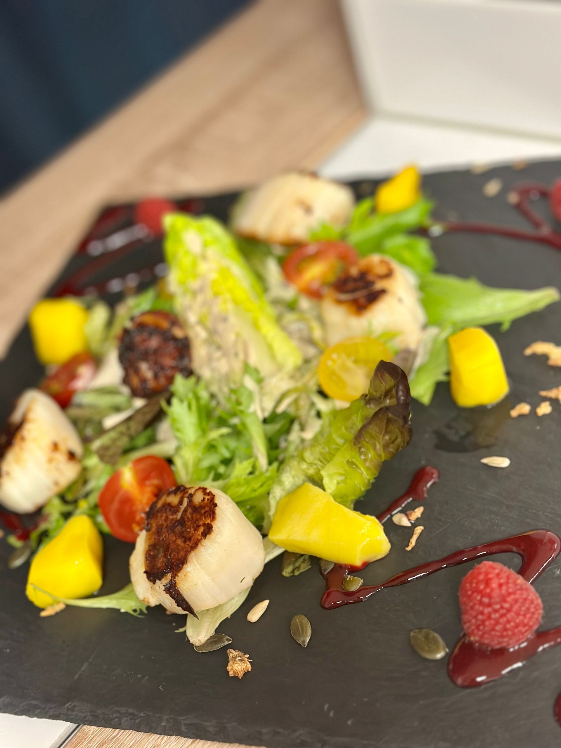 Assiette grise avec de la salade et des framboises