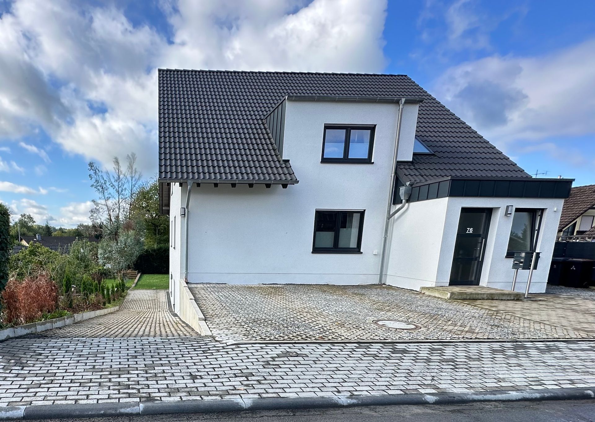 Ein weißes Haus mit schwarzem Dach und schwarzen Fenstern