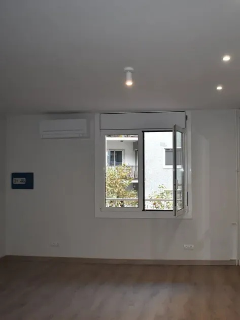 Habitación vacía con una ventana abierta, unidad de aire acondicionado y lámpara.