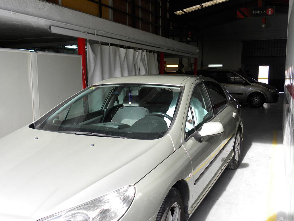 Dos coches aparcados en un garaje. Uno es plateado, al frente. Otro, plateado, al fondo.