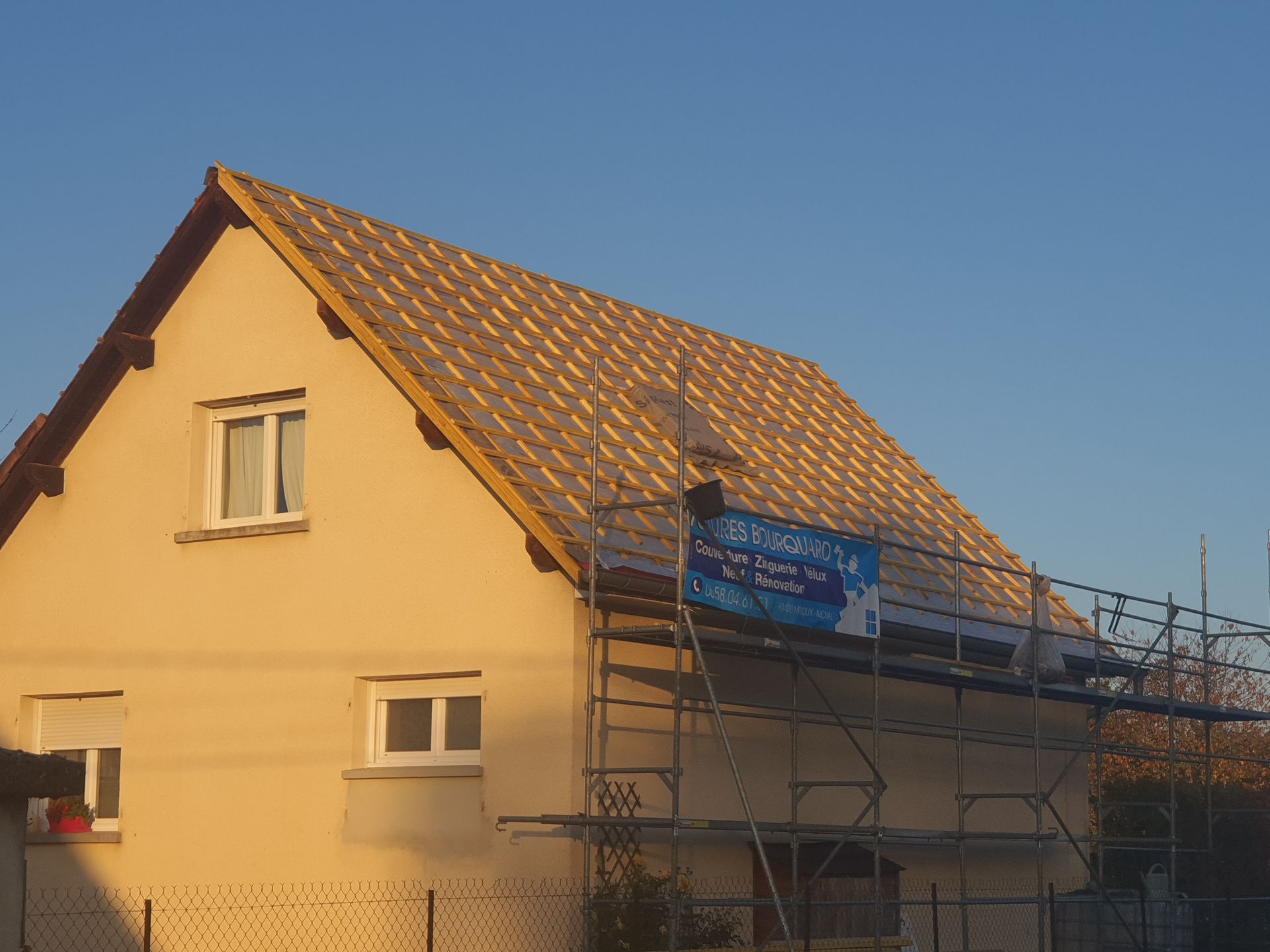 Maison en construction avec une nouvelle toiture ; échafaudages sur le côté.