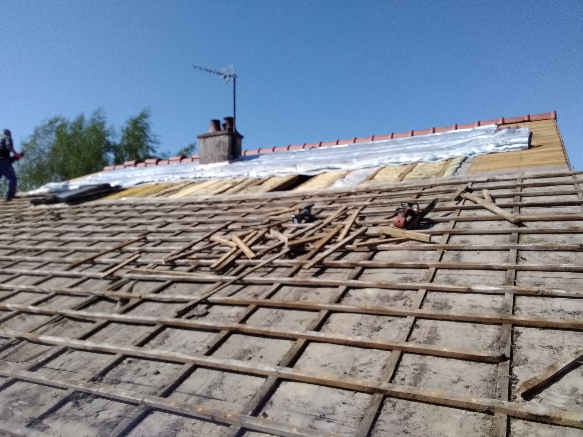 Toiture avec charpente apparente, sous-toiture et une personne travaillant dessus.