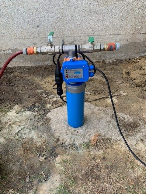 Eine blaue Wasserpumpe steht neben einem Schlauch auf dem Boden.