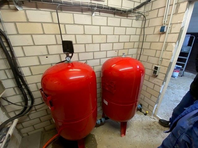 Zwei rote Tanks in einem Raum mit einer Ziegelwand