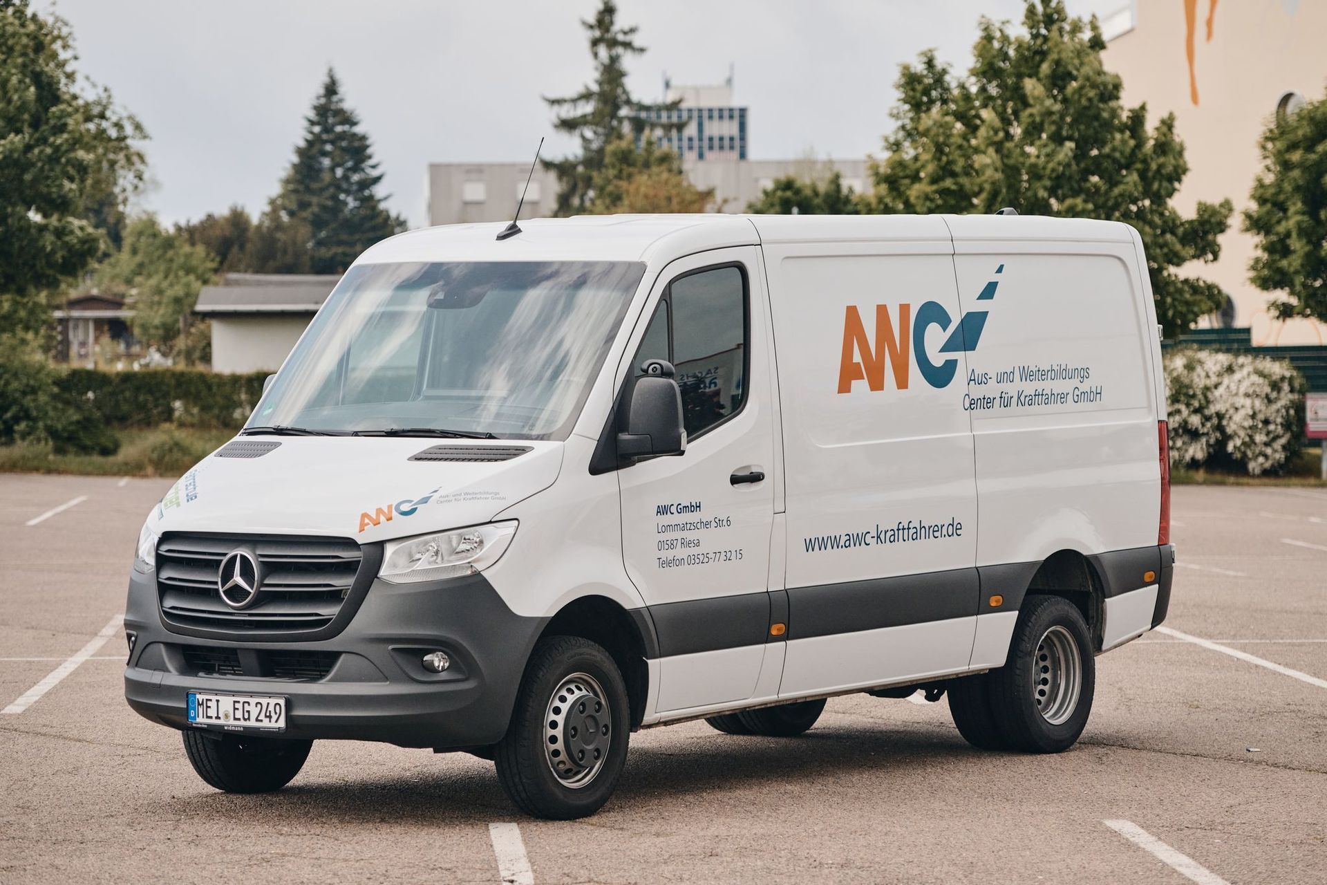 Draußen parkt ein weißer ANC-Van mit Logo an der Seite.