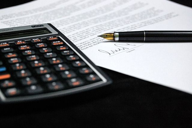 Hay un bolígrafo sobre un trozo de papel junto a una calculadora.