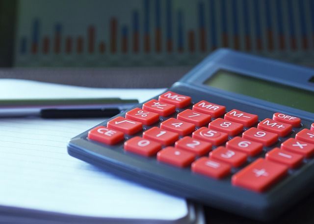 Una calculadora está sobre un trozo de papel al lado de un bolígrafo.