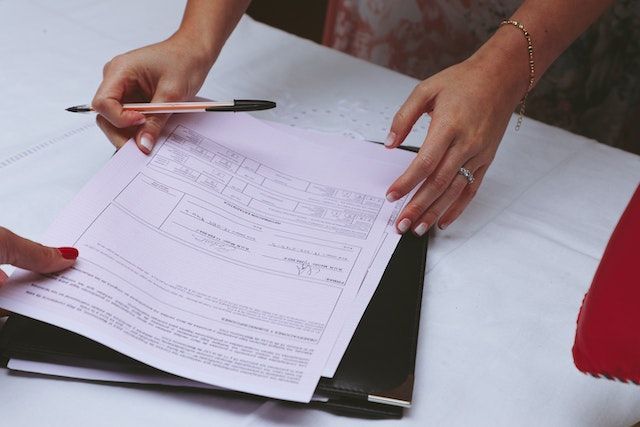 Una mujer sostiene un bolígrafo sobre un trozo de papel.