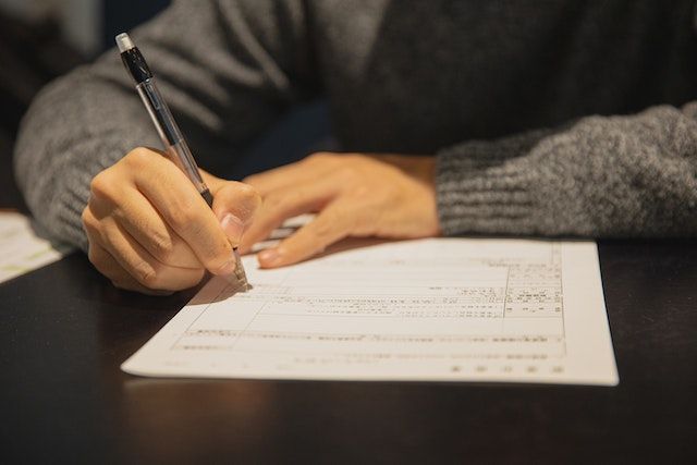 Una persona está escribiendo en un trozo de papel con un bolígrafo.