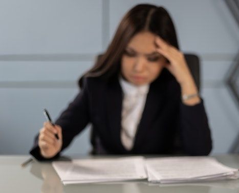 Una mujer está sentada en un escritorio escribiendo en un cuaderno.