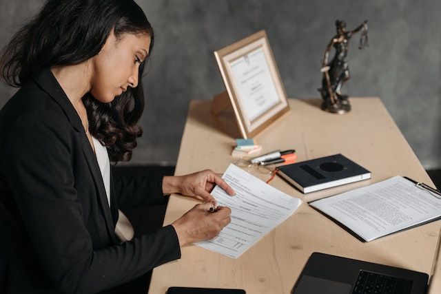 Una mujer está sentada en un escritorio mirando un trozo de papel.