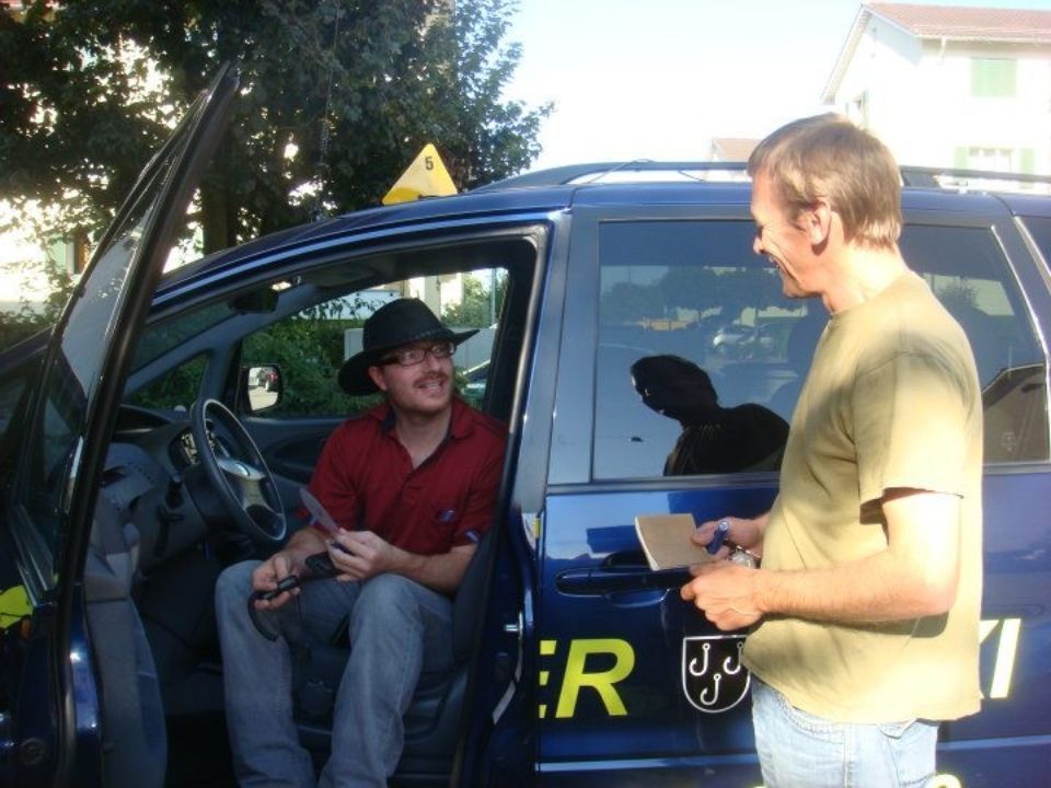 Zwei Männer diskutieren neben einem Taxi