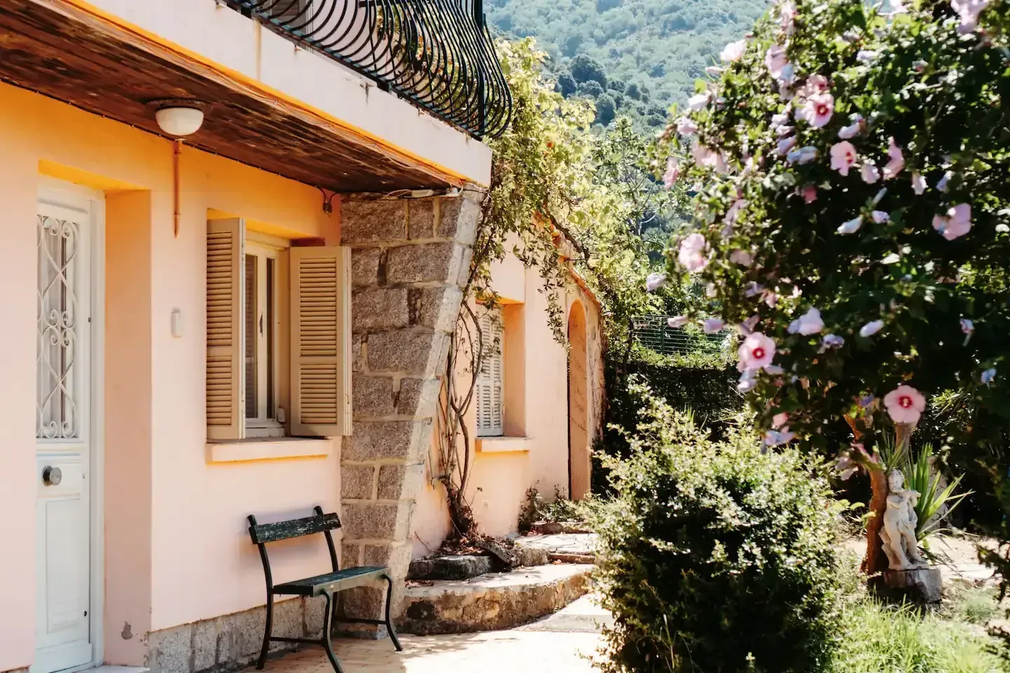 Una casa rosa con un banco delante de ella.