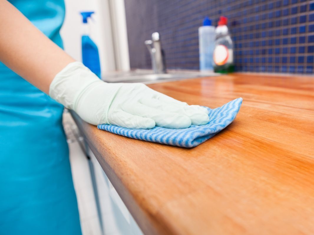 Una persona está limpiando un mostrador de madera con un paño.