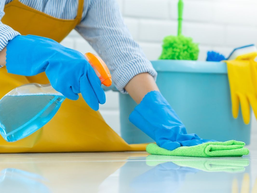 Una persona que lleva guantes azules está limpiando el suelo con un paño.