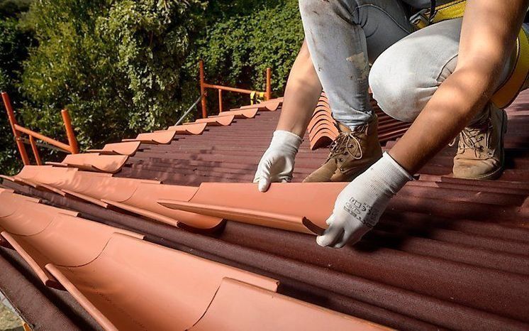 Un hombre está instalando tejas en el tejado de una casa.