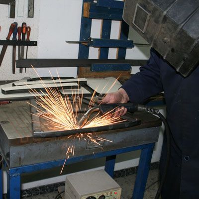 Un hombre que lleva un casco de soldador está puliendo un trozo de metal.