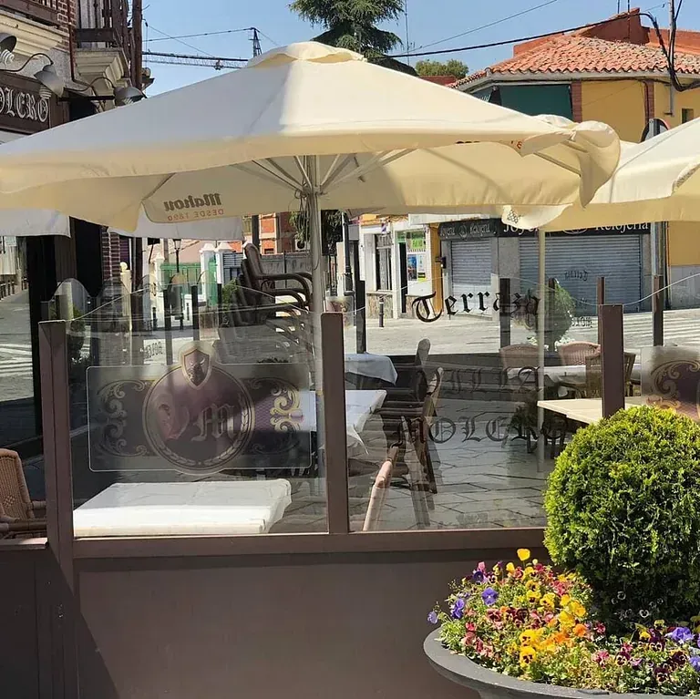 Un restaurante con sombrillas y flores delante.