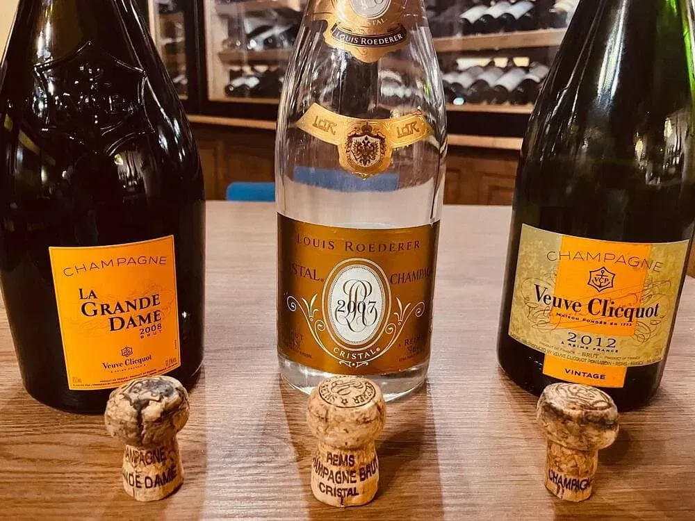 Tres botellas de champán están sobre una mesa de madera.