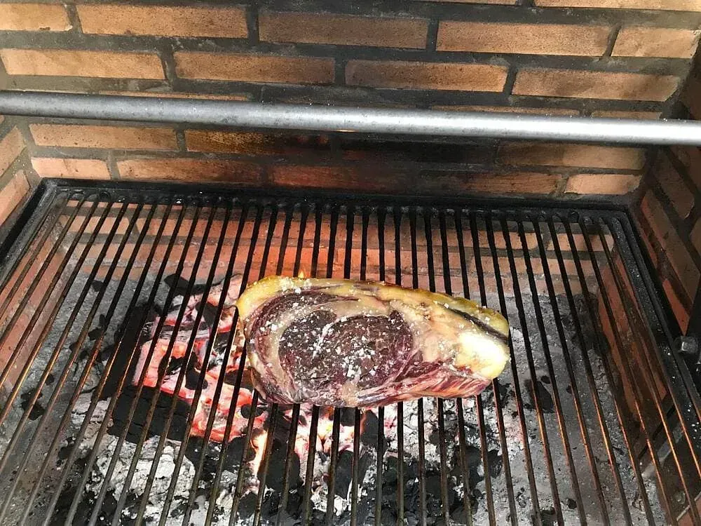 Un gran trozo de carne se está cocinando en una parrilla.