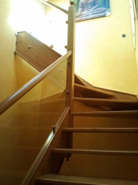 Escalera de madera con pasamanos contra una pared de color amarillo claro.