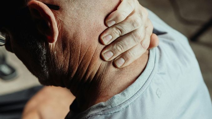 Persona que se lleva la mano a la nuca, probablemente sintiendo dolor.