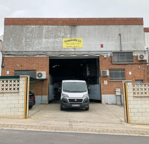 Una camioneta blanca está estacionada frente a un edificio de ladrillos.