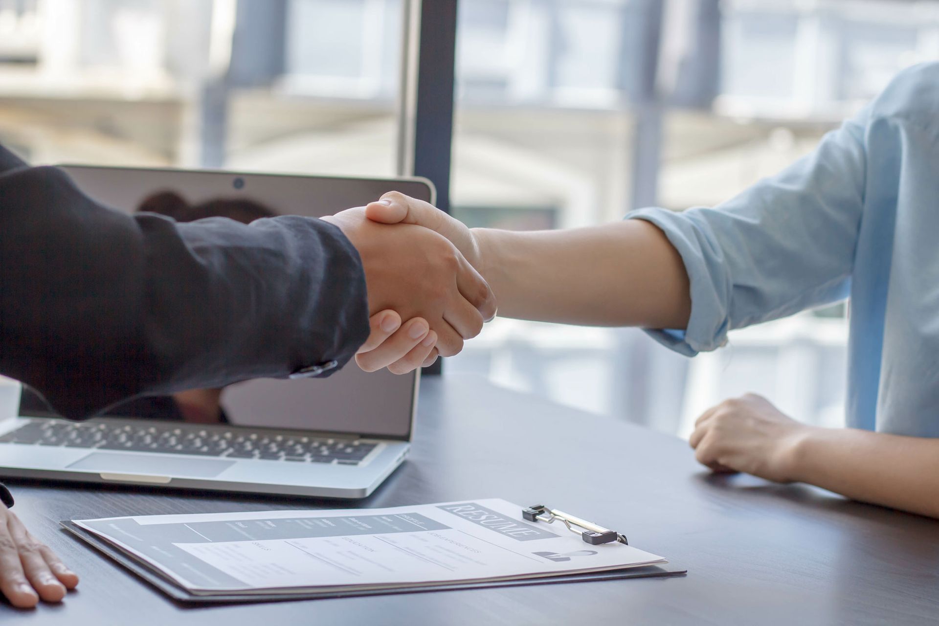 Ein Mann und eine Frau schütteln sich an einem Tisch die Hand.