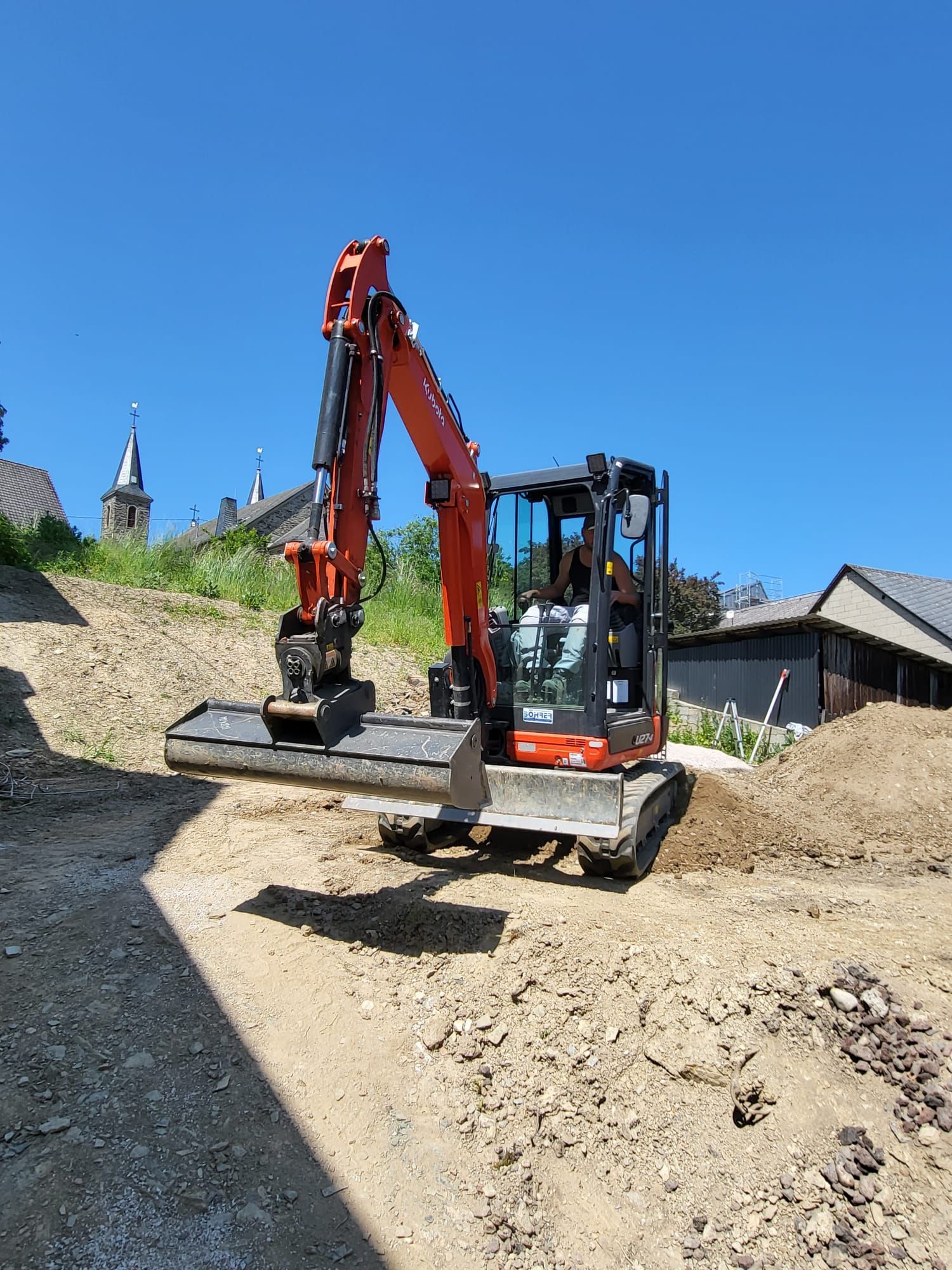 Ein rot-schwarzer Bagger steht auf einem Erdfeld.