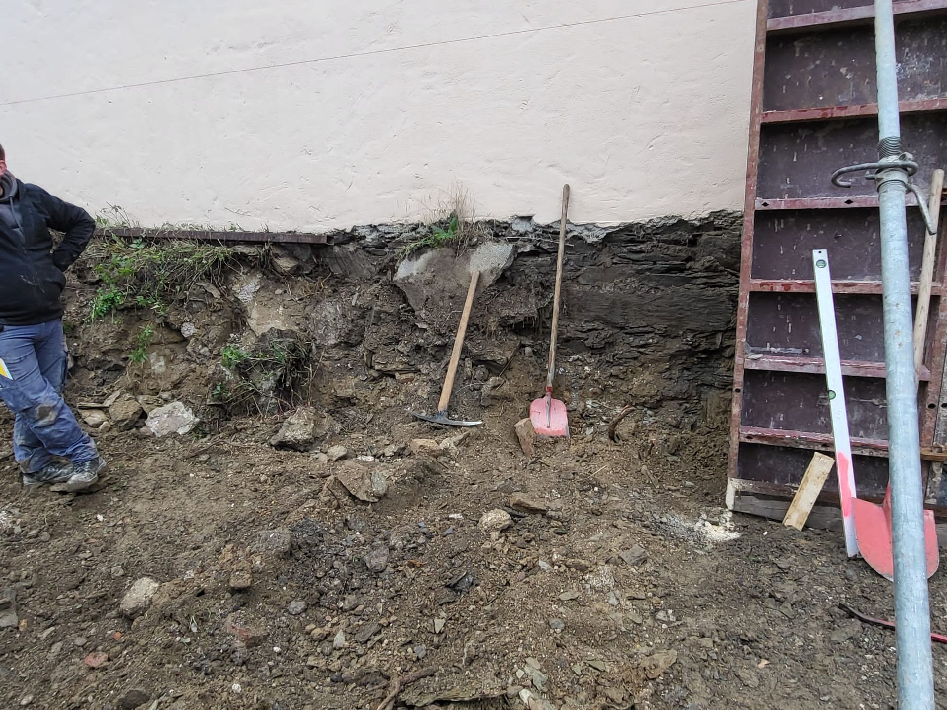 Ein Mann steht neben einem Erdhaufen und einer Schaufel.