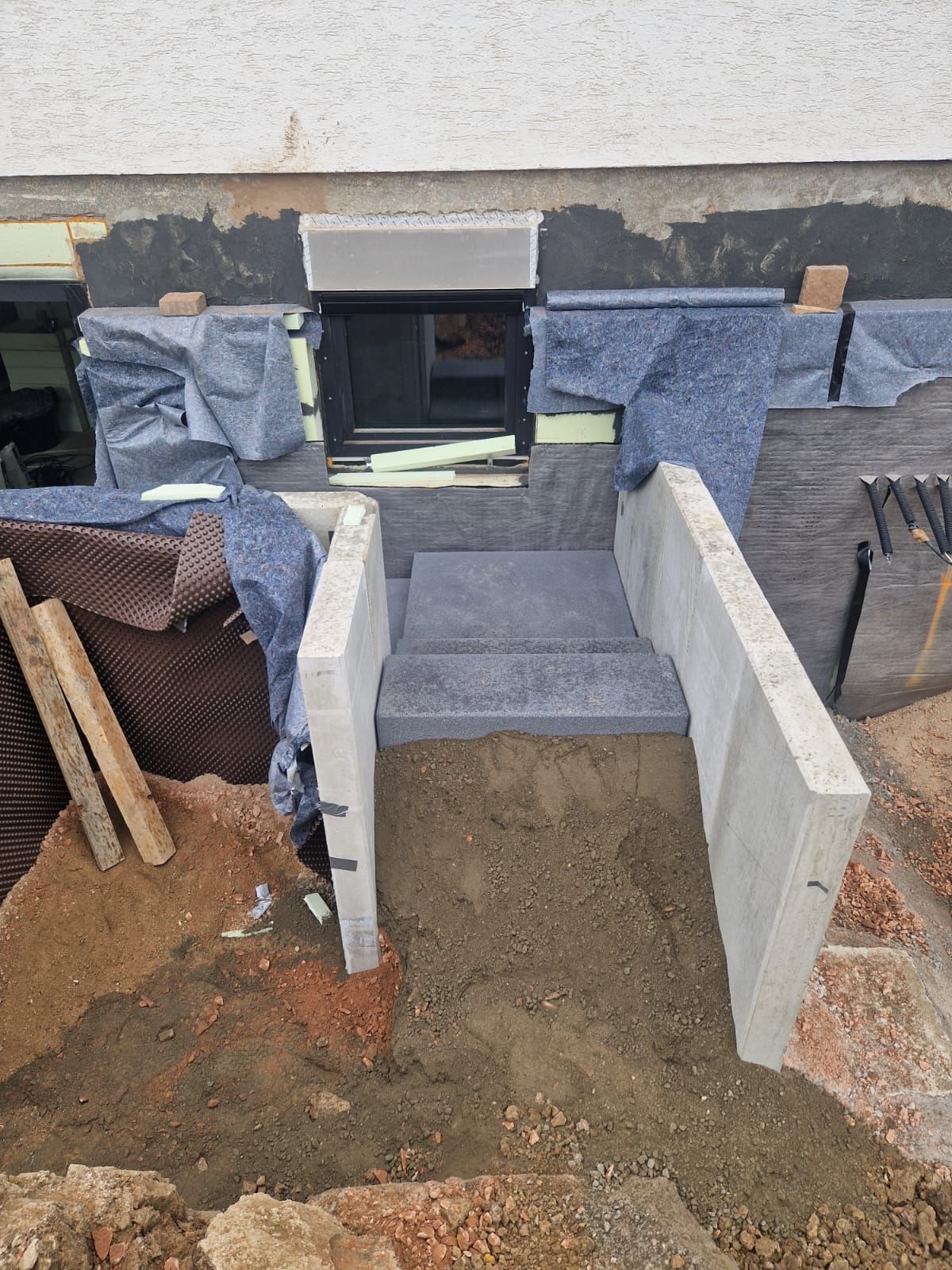 Vor einem Gebäude wird eine Betontreppe in den Boden gebaut.