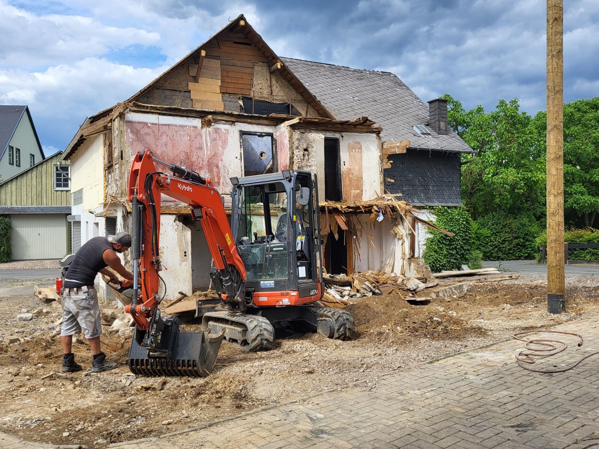 Ein Mann steht vor einem Haus, das abgerissen wird.