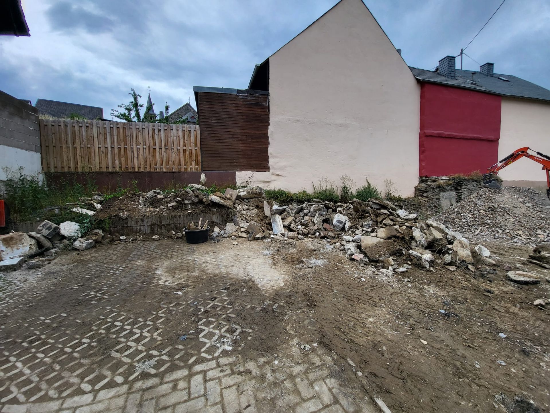 Vor einem Gebäude mit einer roten Tür liegt ein großer Erdhaufen.