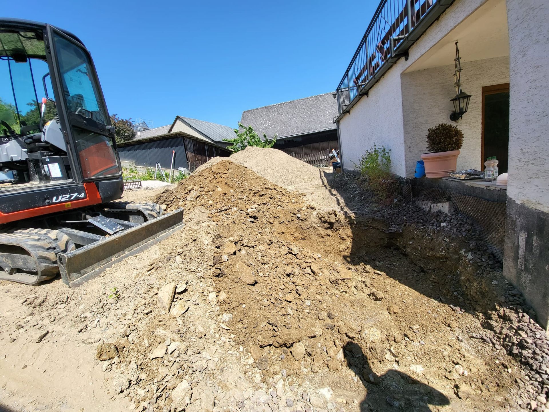 Eine Planierraupe bewegt einen Erdhaufen vor einem Haus.