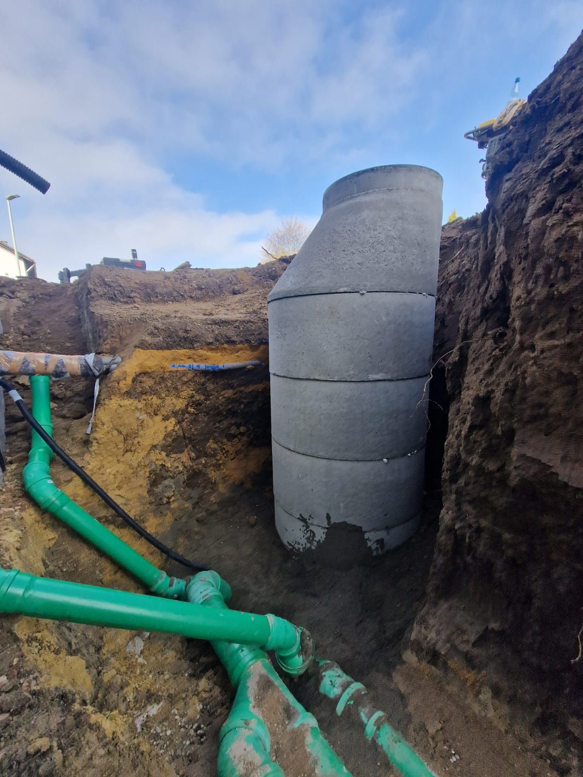 In der Mitte eines Grabens liegt ein Betonring, umgeben von grünen Rohren.